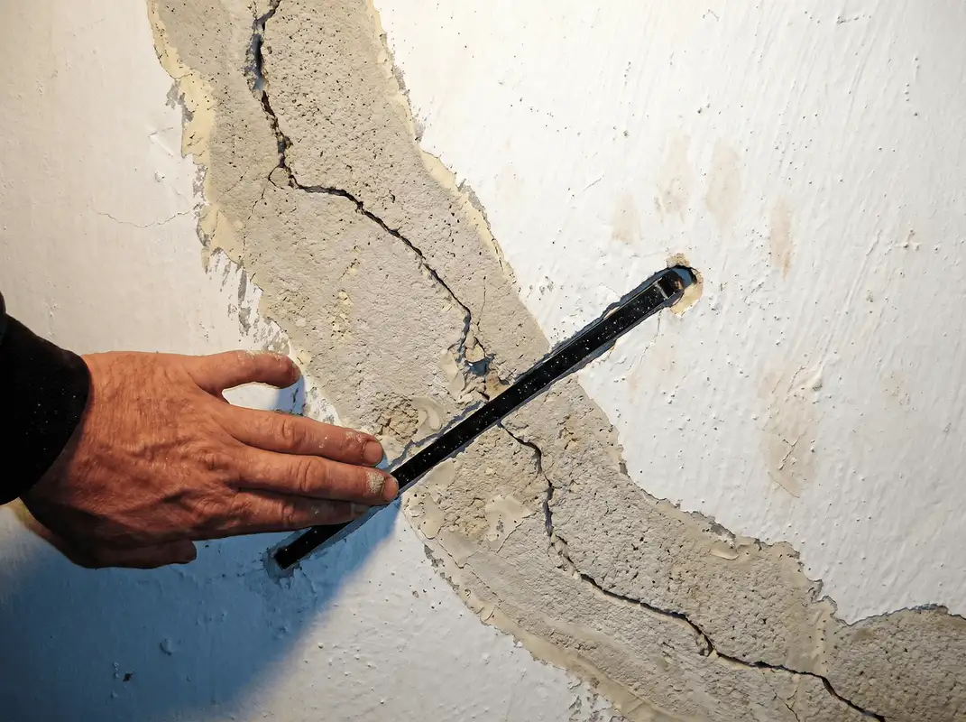 A wall with a large crack is being inspected by a professional in Pueblo, CO